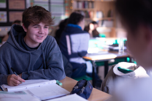 Boy writing and talking to another person