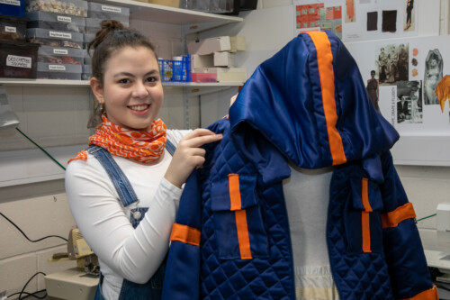 Fashion student standing with garment on mannequin